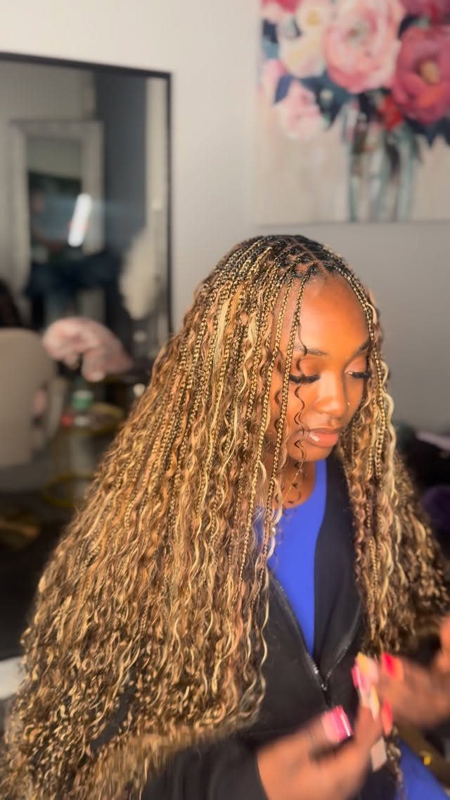 Woman wearing long brown braids with lighter blonde highlights and curly ends