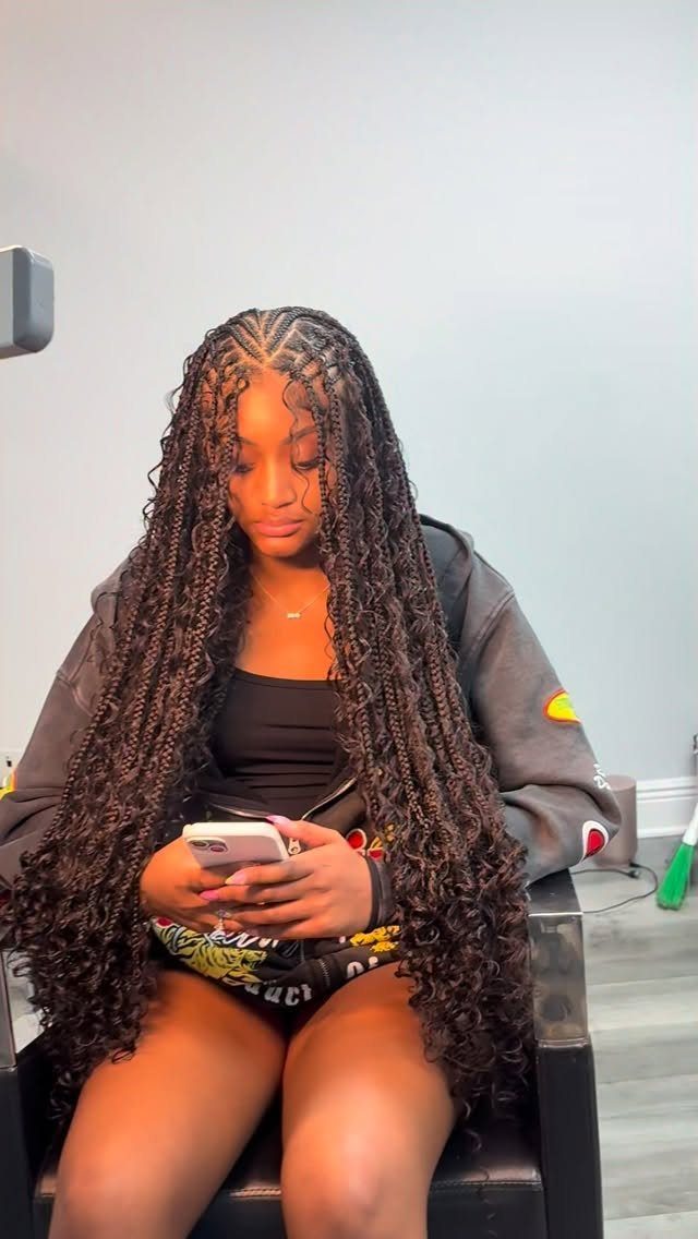 Woman seated in a salon wearing long small dark Fulani braids