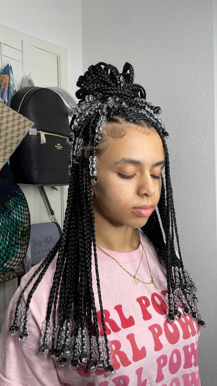 Person wearing long beaded braids in a high half-up bun with loose lengths