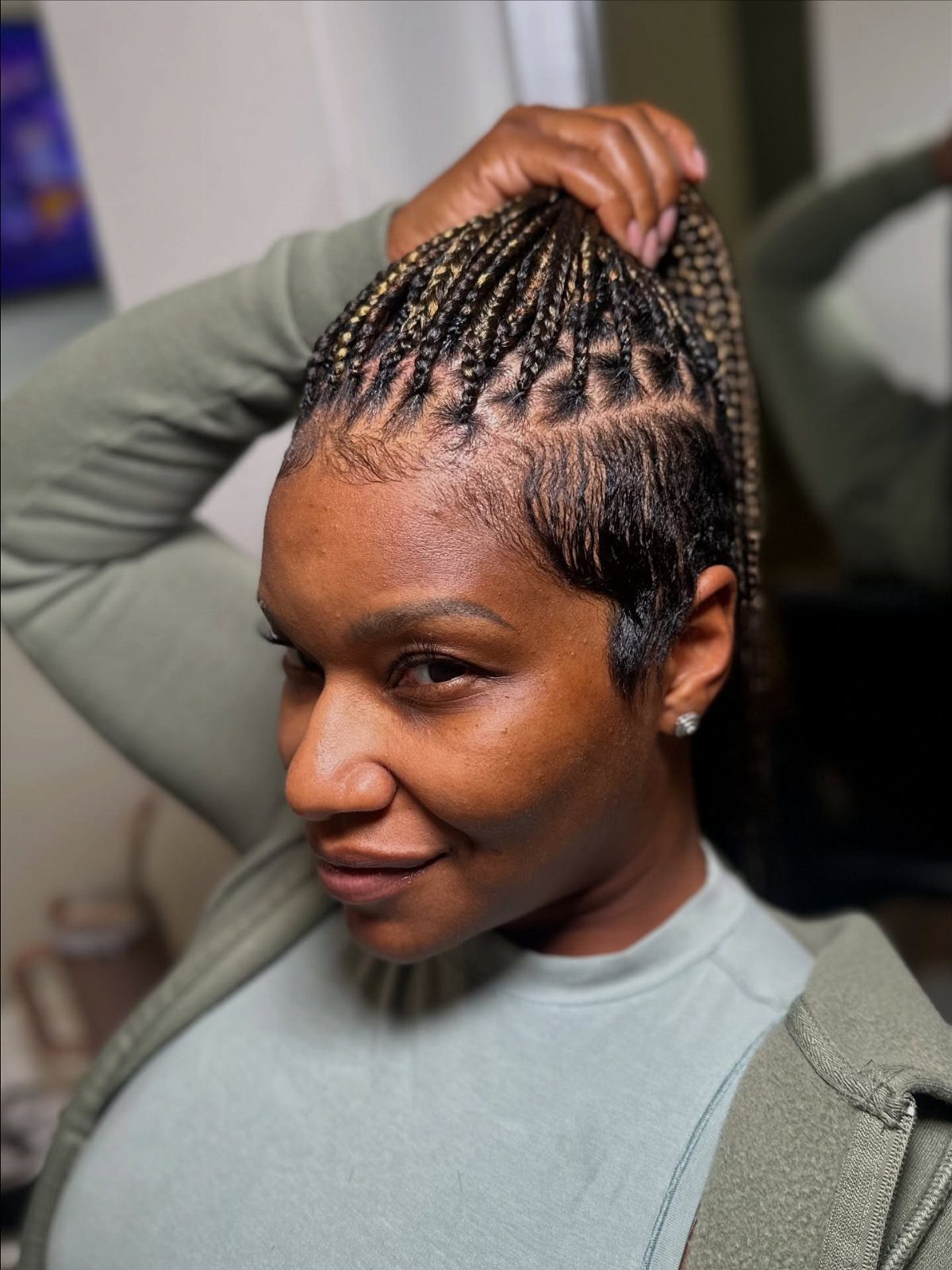 Woman showing small braids swept into a mohawk with closely shaved sides