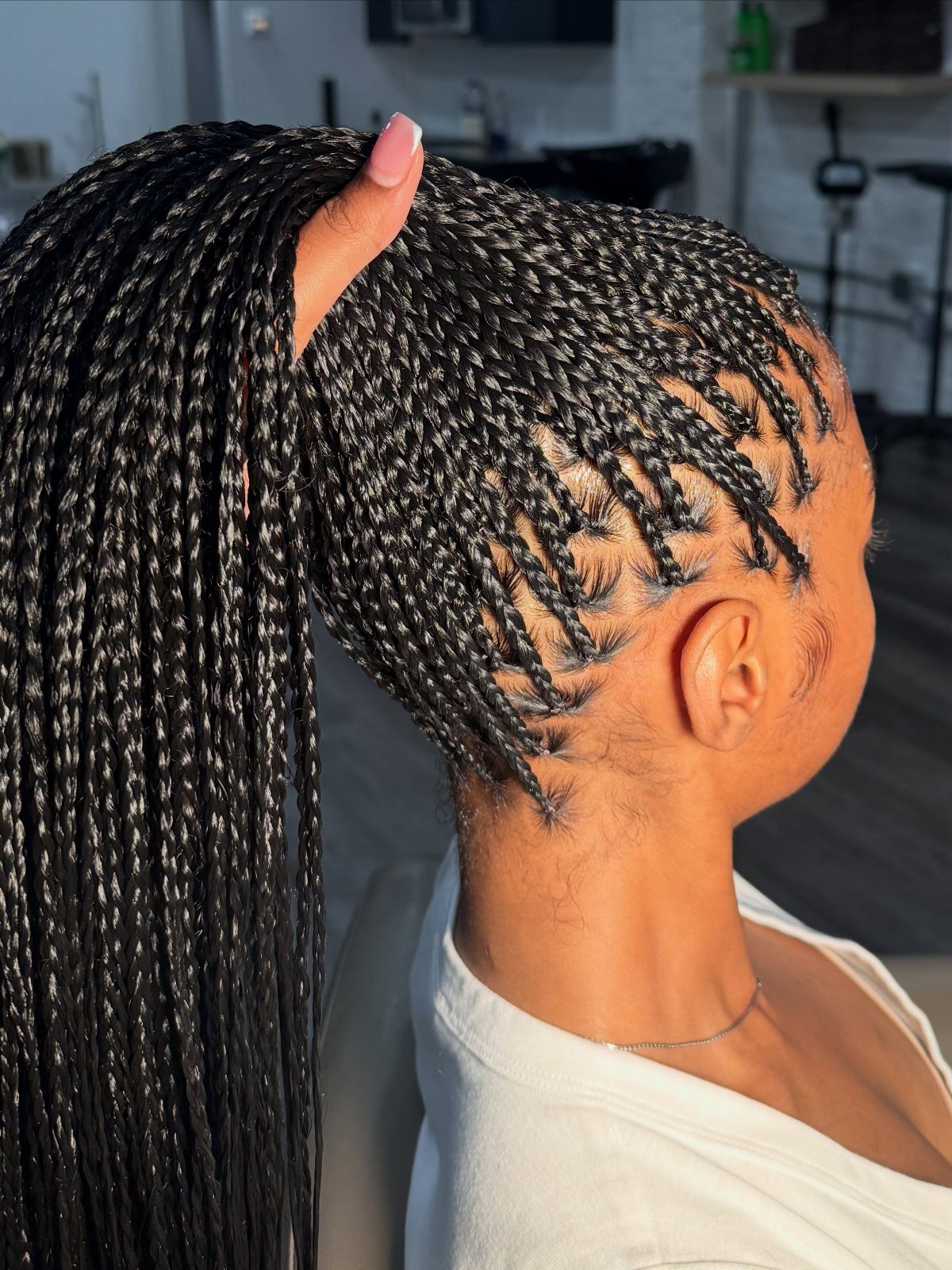 Small black knotless braids gathered into a high ponytail with neat scalp parting