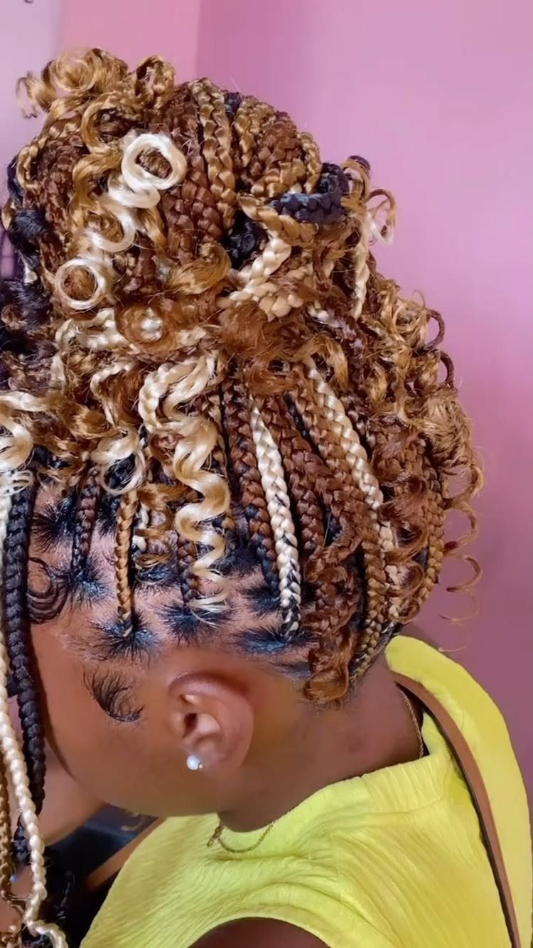 Small braids gathered into a curly updo with blonde accents and loose curled ends