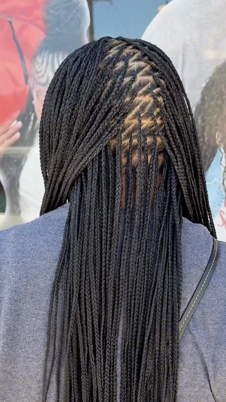 Long black knotless braids show zigzag parting across the scalp