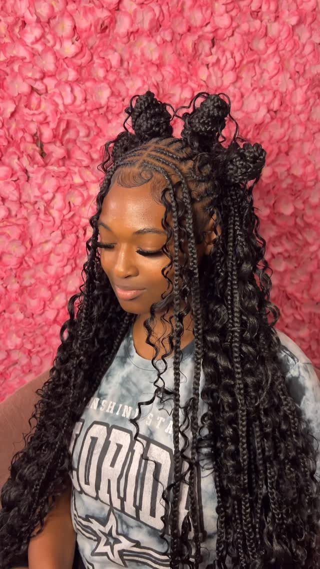Woman with long black braids styled into multiple buns against a pink backdrop