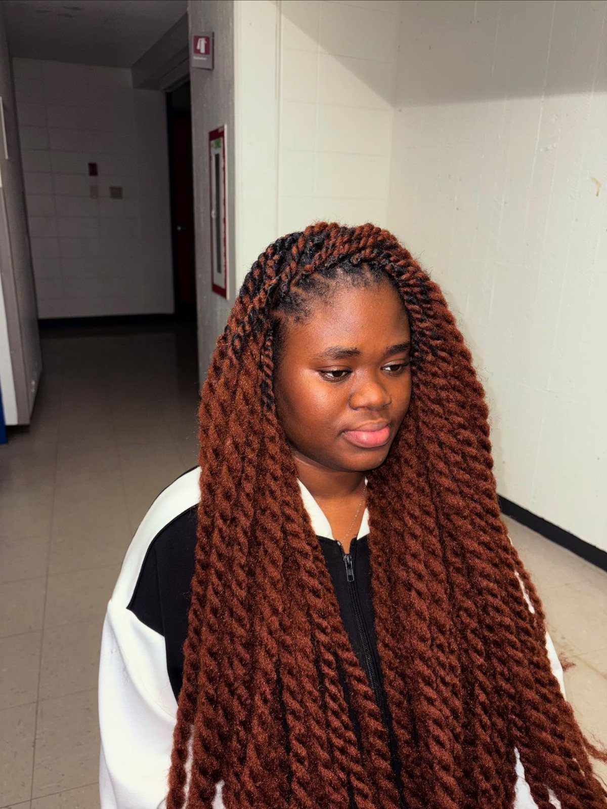 Woman wearing long, chunky chocolate-brown twists in a tiled hallway