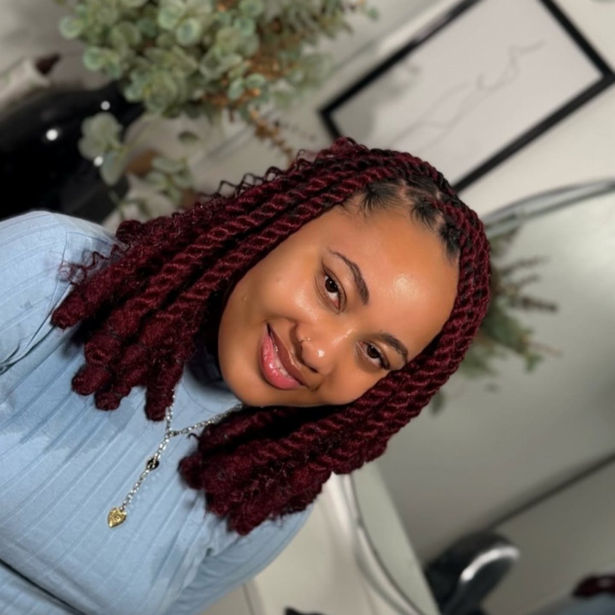 Woman displaying chunky shoulder-length burgundy Marley twists with visible twisted roots
