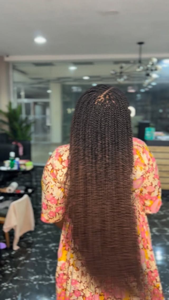 Extra-long dark brown twists fall down the back below the waist in a salon.