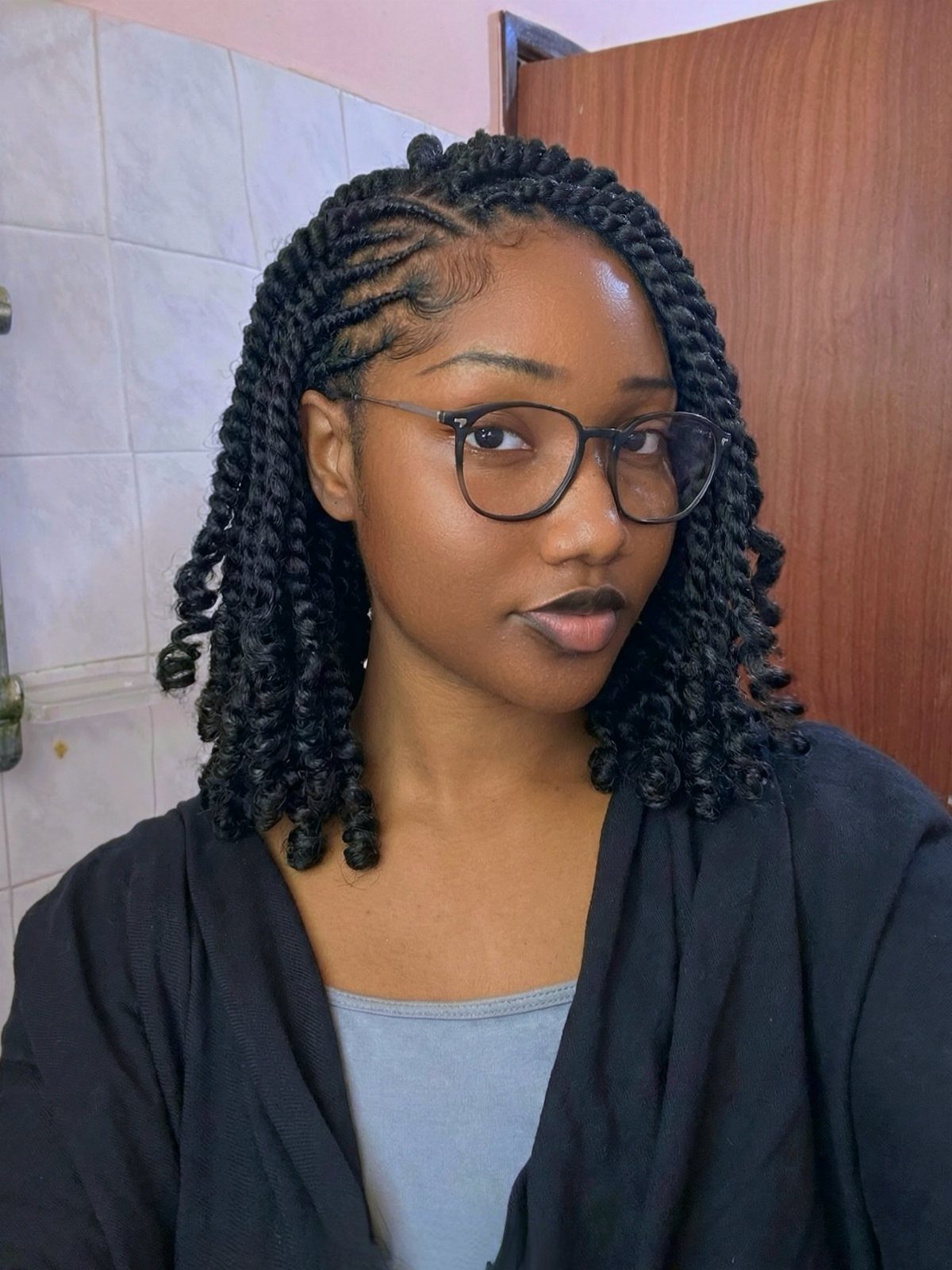Woman wearing shoulder-length Marley twists with braided roots and glasses