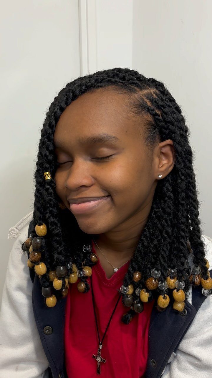Person wearing long Marley twists decorated with black, amber, and gold hair charms