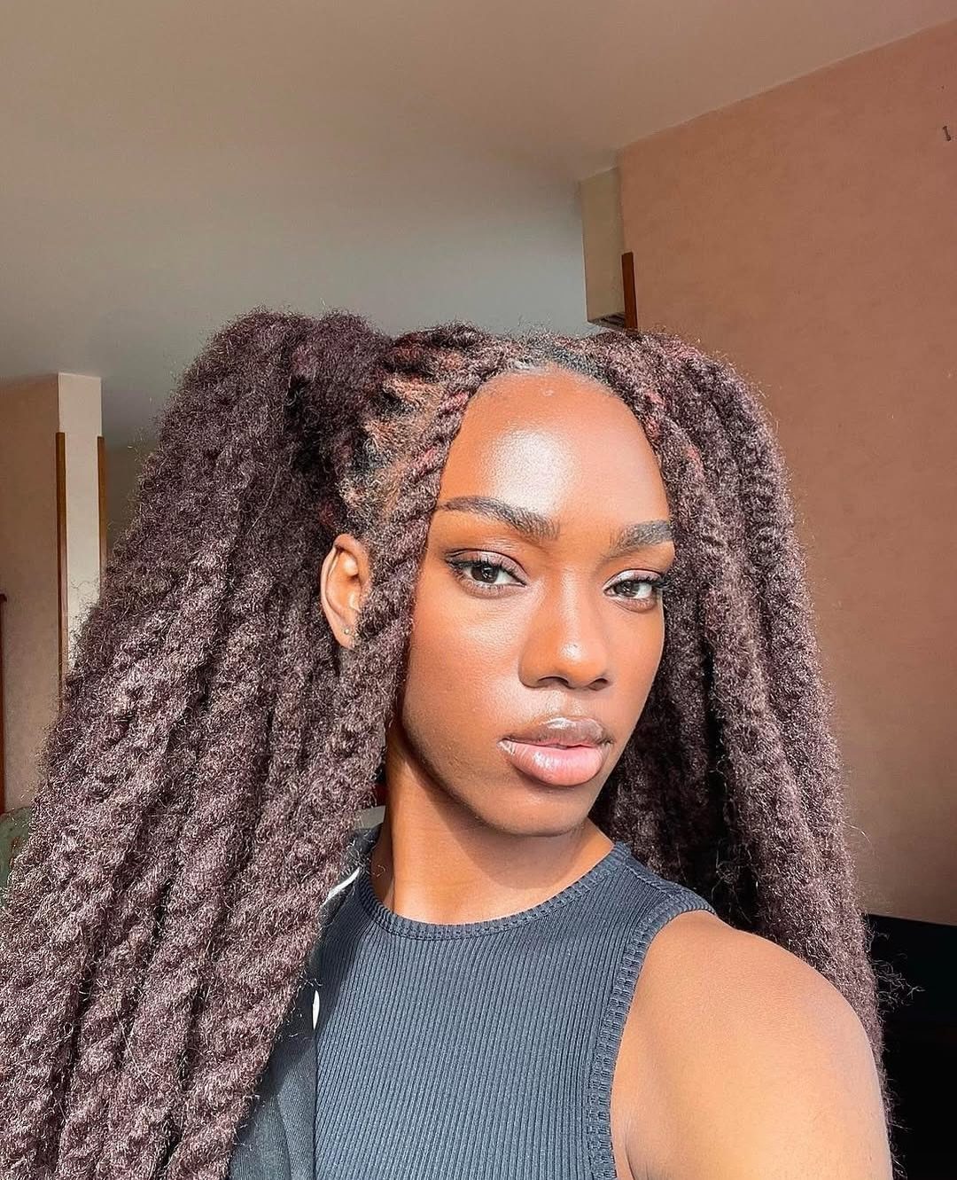 Woman with sleek roots and long, soft, poofy Marley twists framing her face