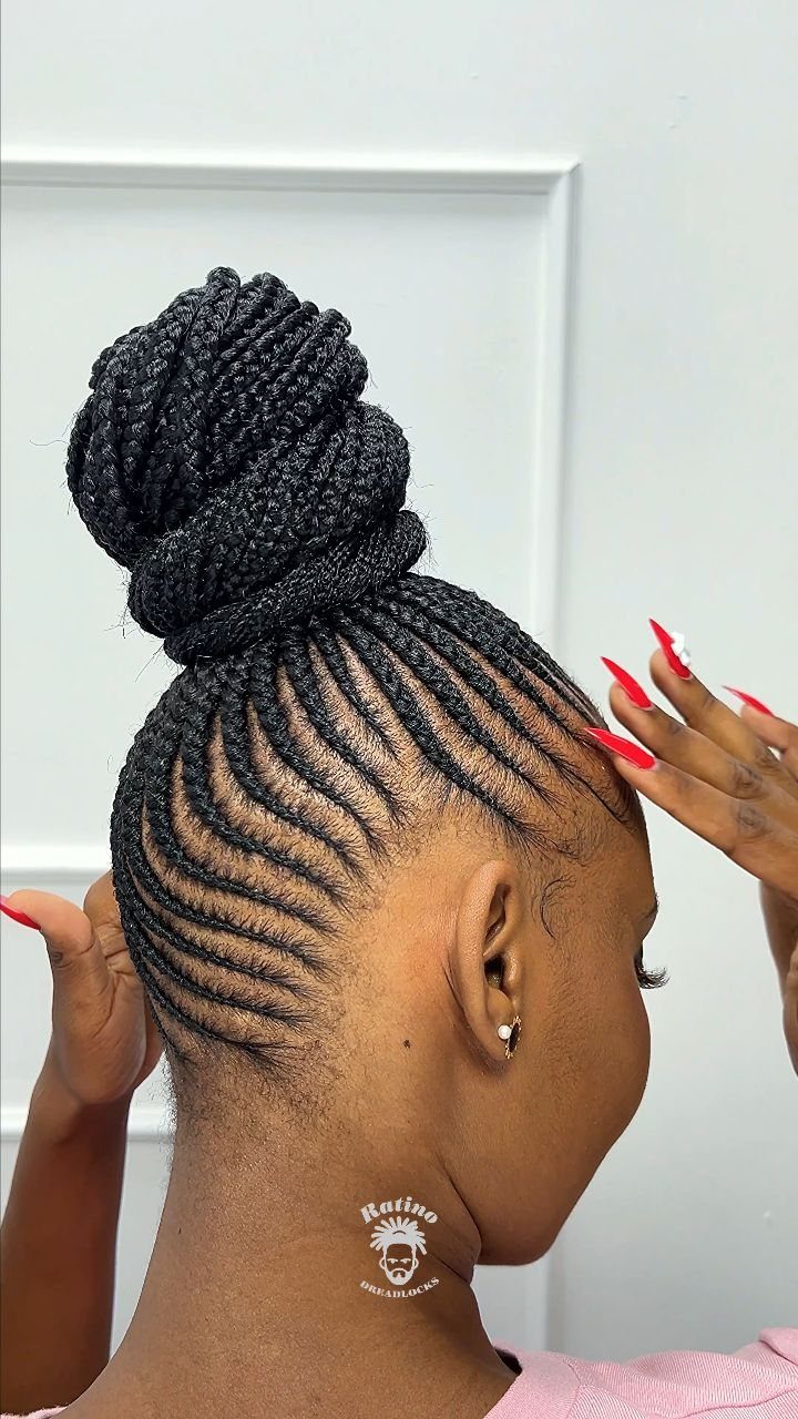 Curved cornrows sweep into a large twisted bun atop the head