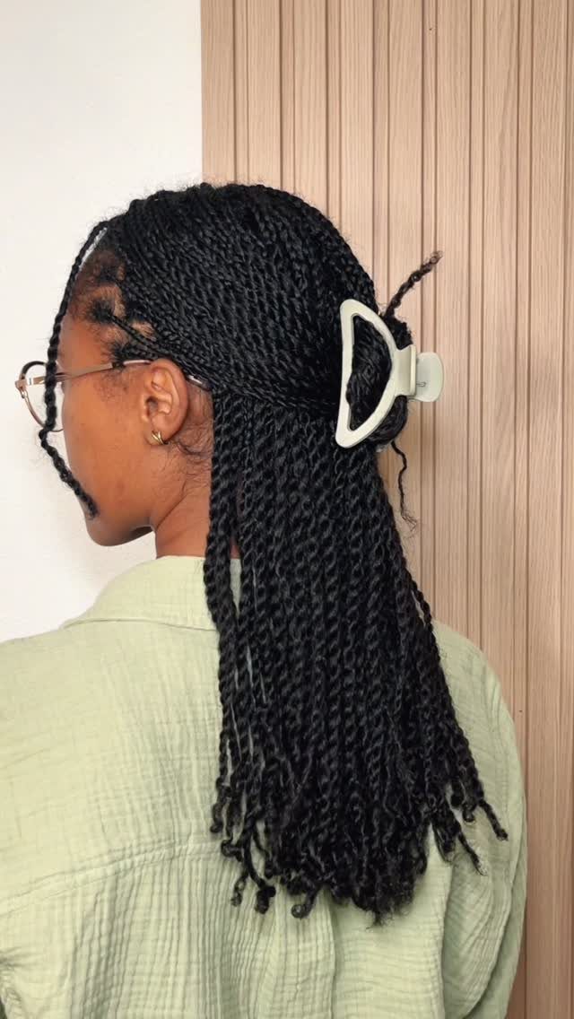 Small black twists are half gathered with a white claw clip