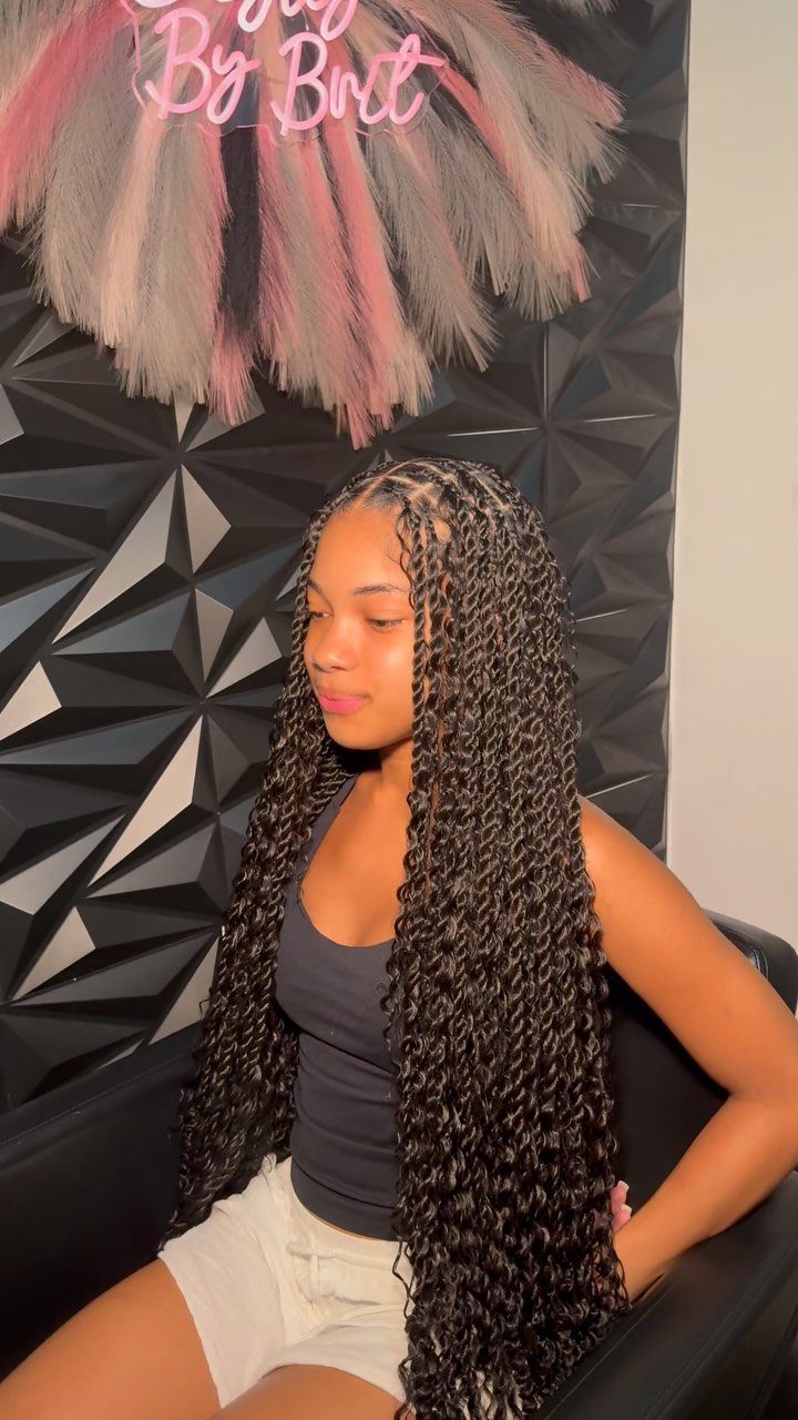 Woman posing with long, medium-width dark twists against a geometric wall