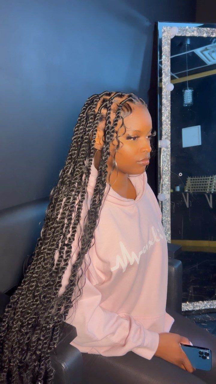 Woman wearing long black passion twists with loose wavy ends in a salon