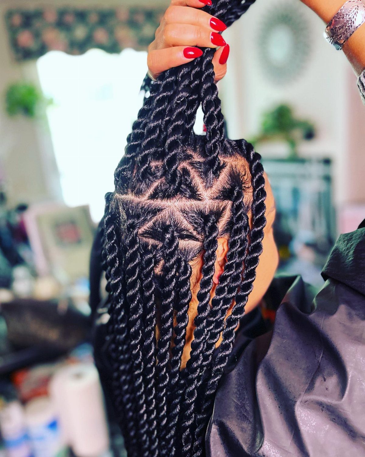 Long black rope twists with geometric scalp parting held up in a salon
