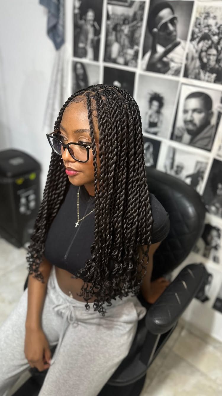 Woman showcasing long Senegalese twists with curly ends in a salon chair