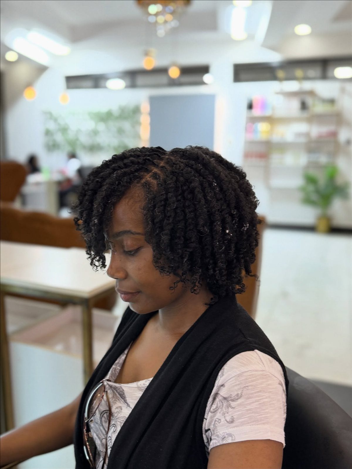Woman with short natural hair styled in small finger twists sitting in a salon