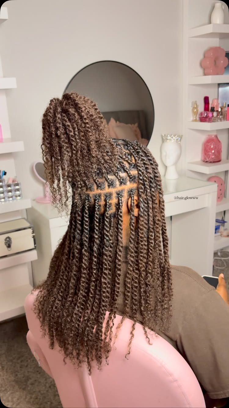 Long highlighted twists gathered into a raised crown on a seated person in a salon