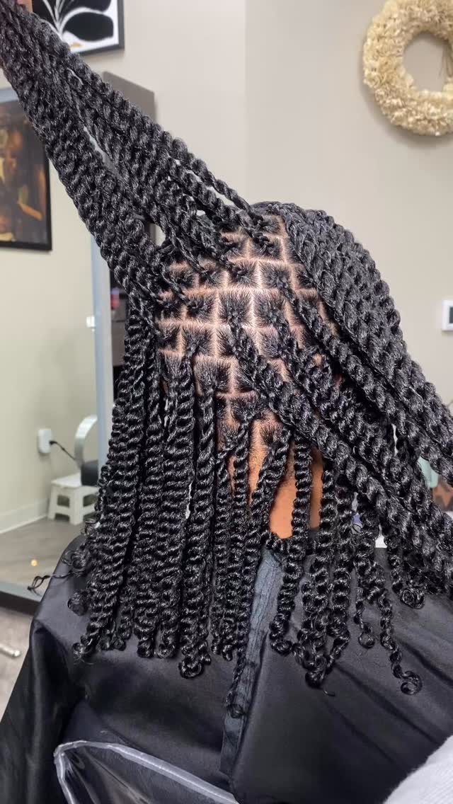 Long black two-strand twists with square parting and curled ends in a salon