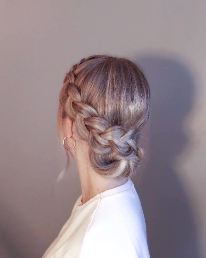 Woman wearing two French braids pinned into a low crown-inspired updo