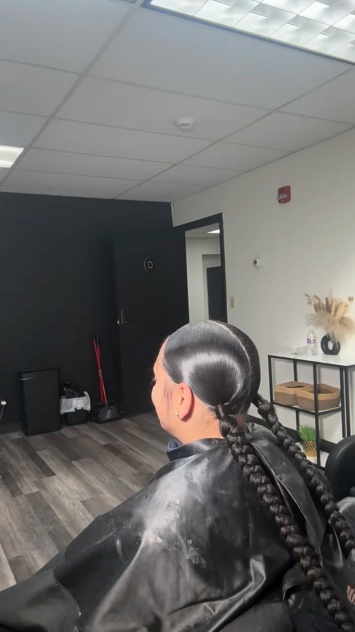 Person with sleek hair styled into two long braids in a salon