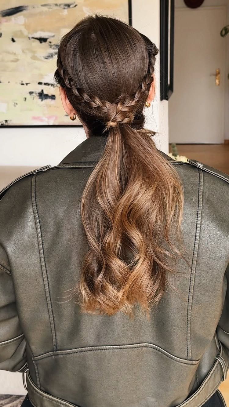 Two short French braids join into a long, loose low ponytail