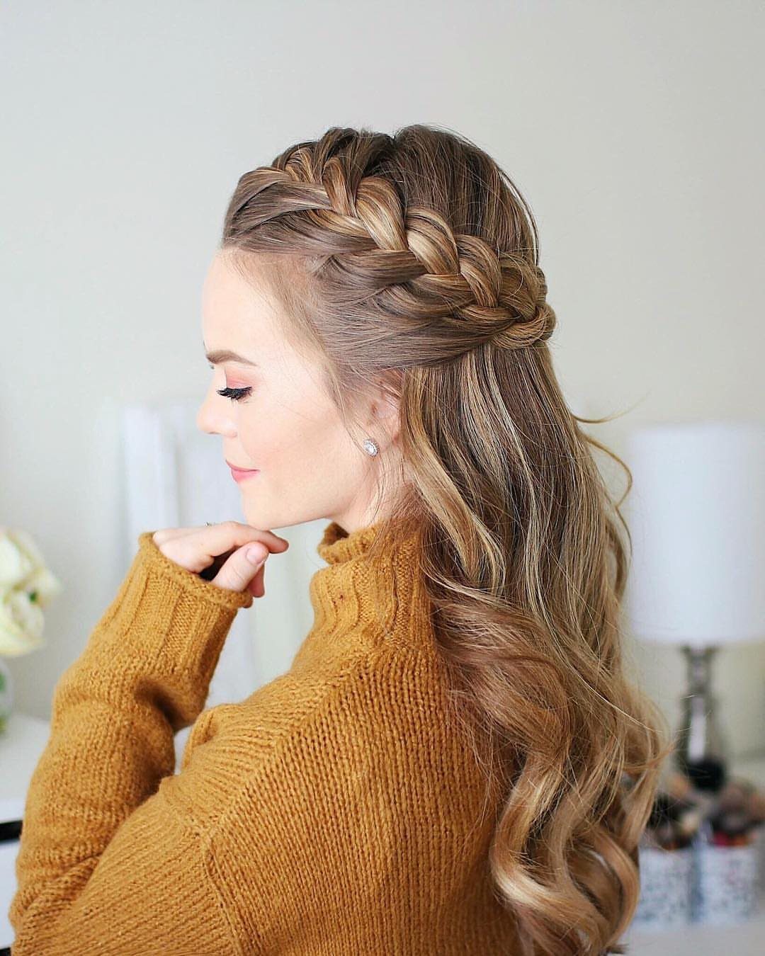 Woman wearing a braided crown with long loose curls and a mustard sweater