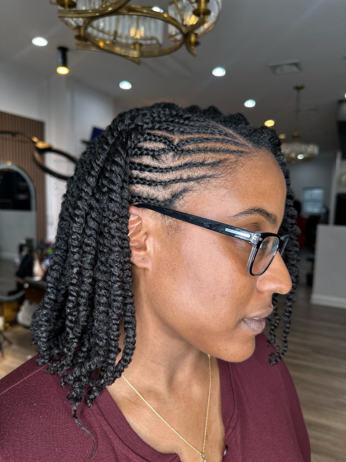 Cornrow rows transition into thick black two-strand twists on a person in a salon