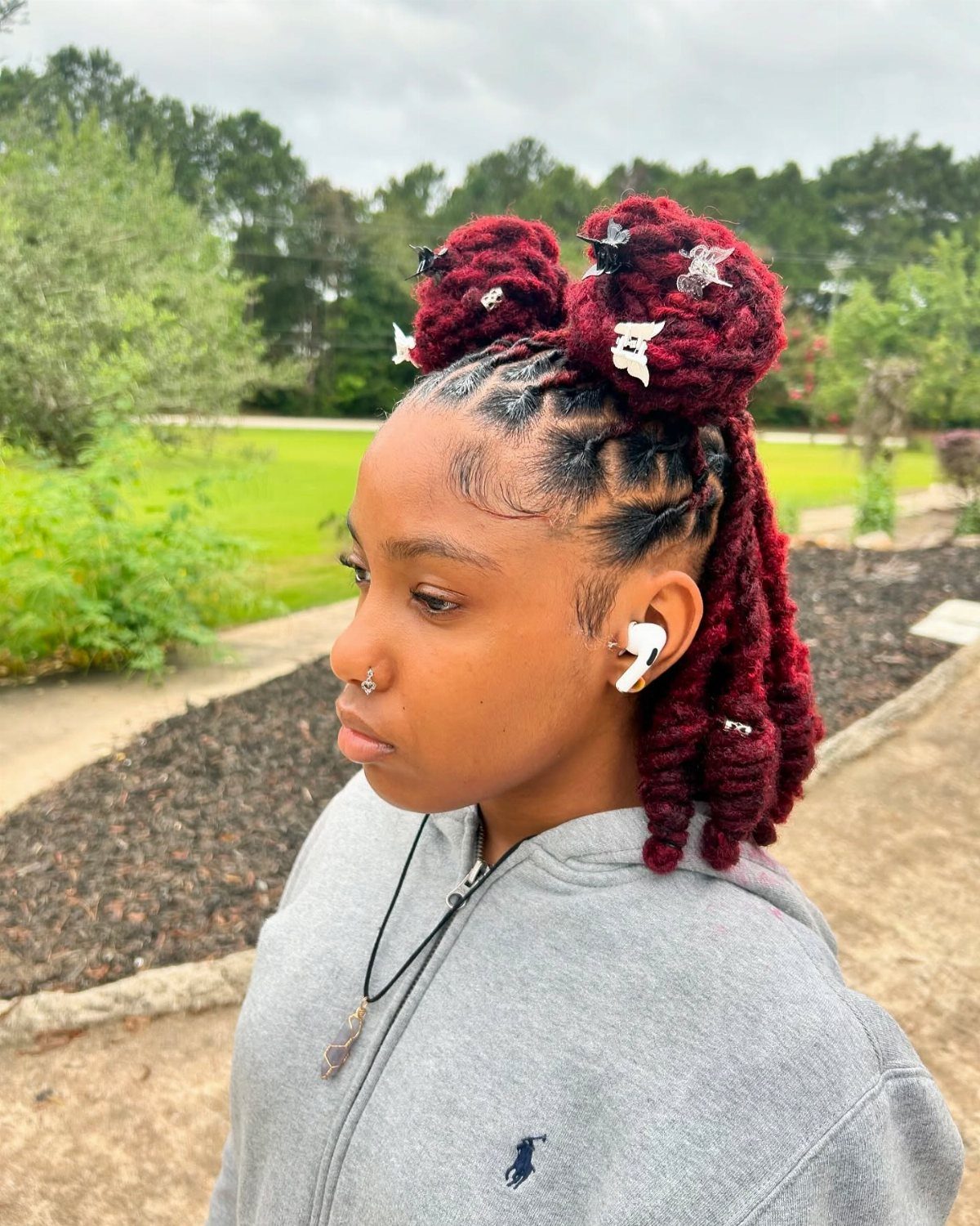 Deep red twists styled half-up in two buns with longer twists hanging behind