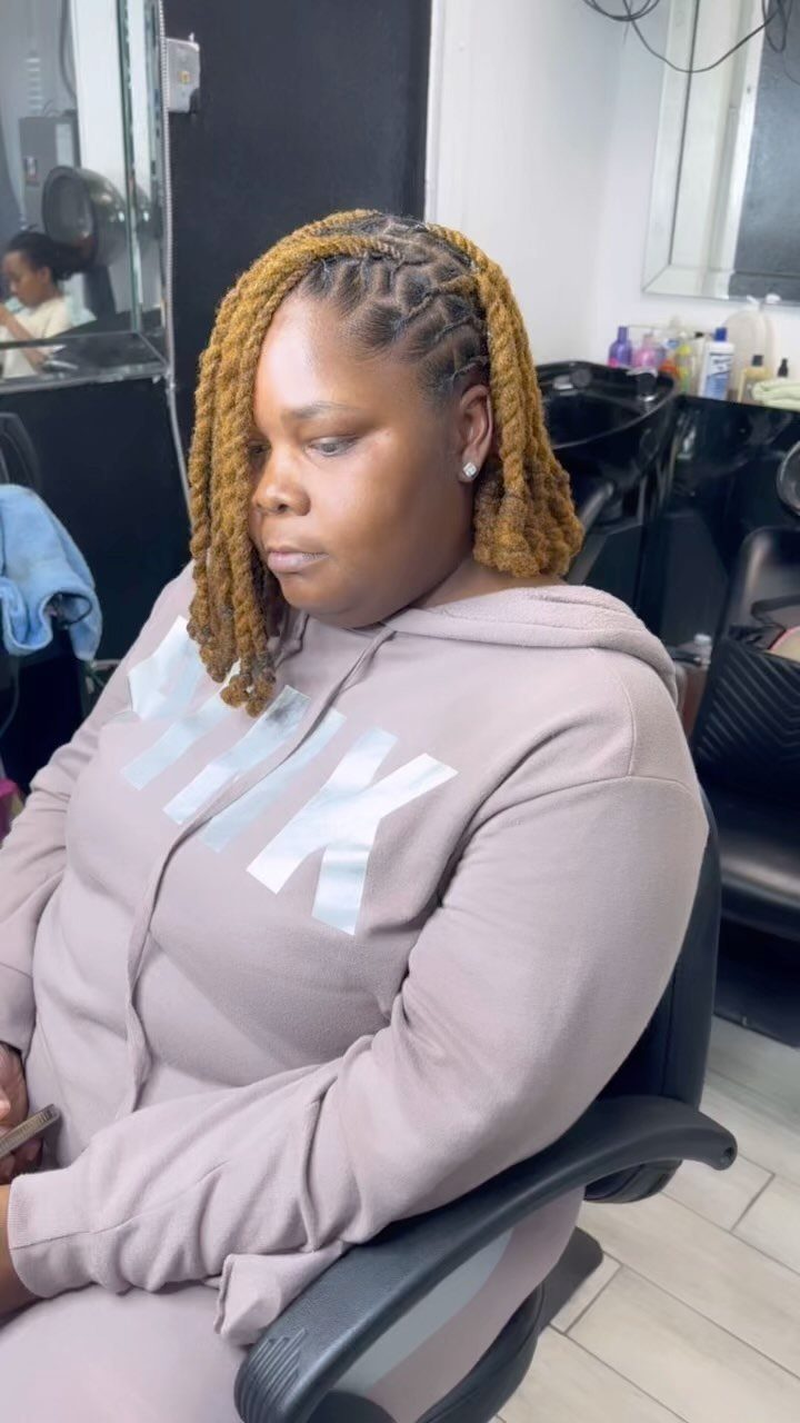 Woman seated in a salon wearing shoulder-length golden-brown natural twists