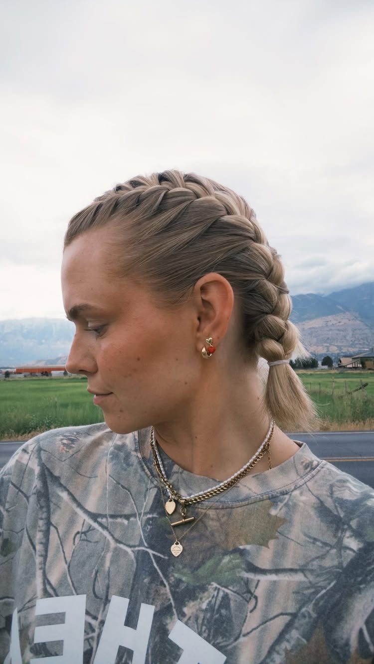 Blonde French braid gathered along the head into a low ponytail
