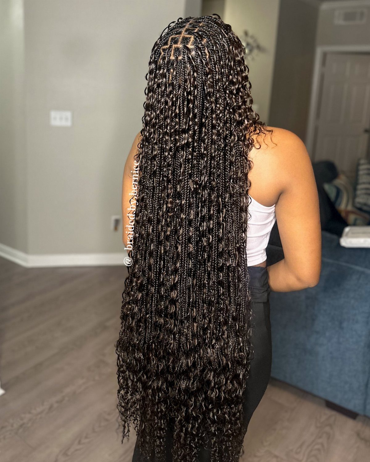 Long dark goddess braids with loose curls trail down a person's back