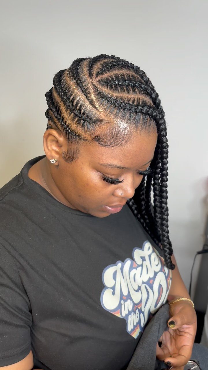 Side-swept black cornrows with a deep part and long braids over her shoulder