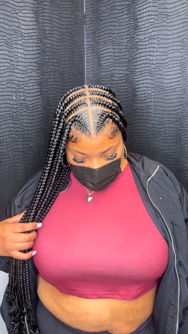 Long center-parted black braids with curved scalp sections frame a masked person.