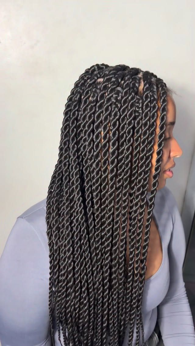 Long black Senegalese twists fall over a woman's shoulder and chest