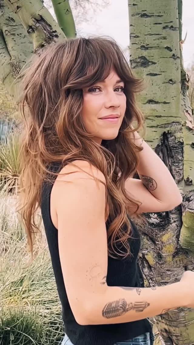 Woman showing a layered shag haircut with wavy fringe and long loose waves