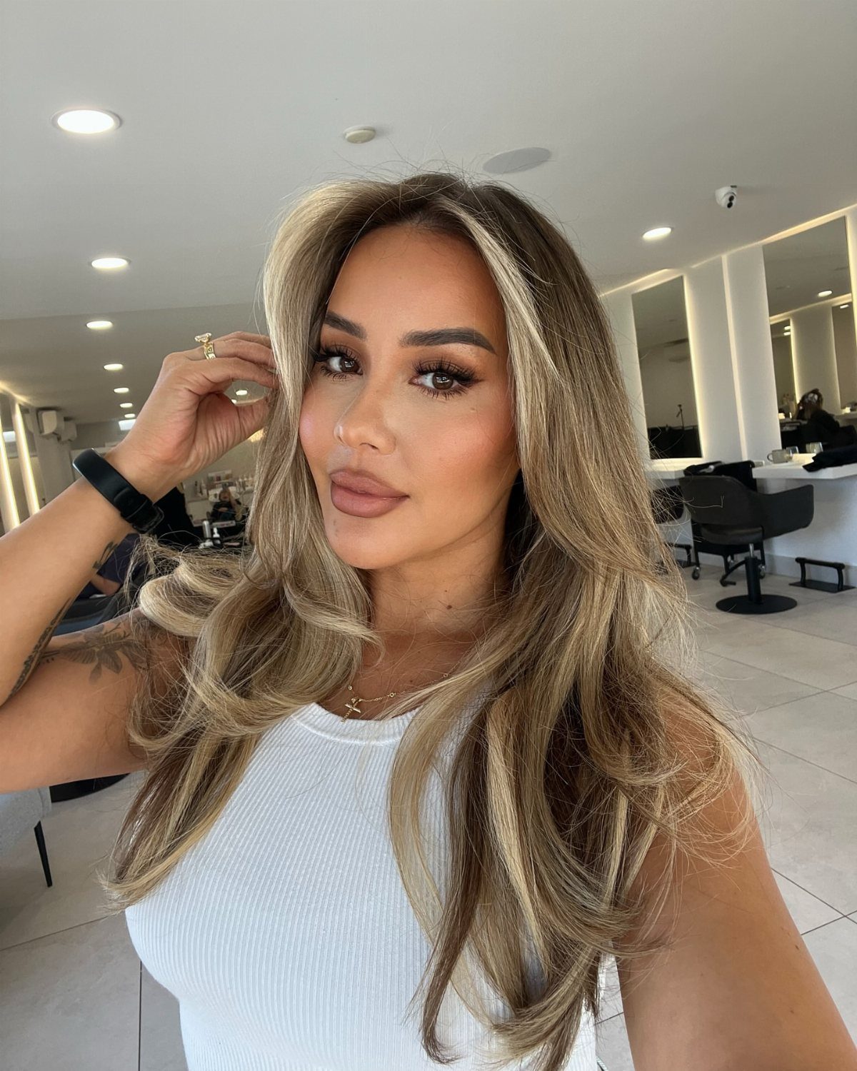 Woman showing long, loose waves with lighter face-framing layers in a salon