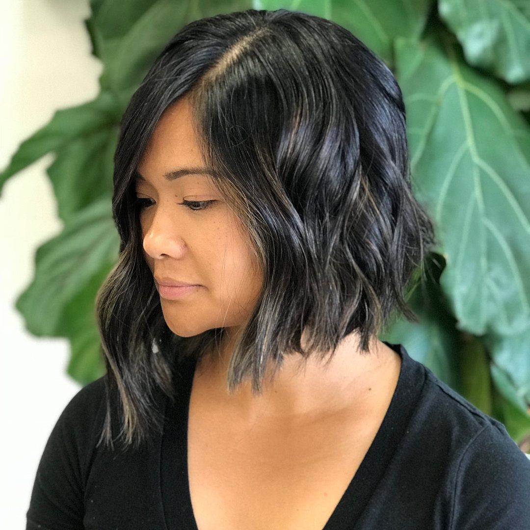 Woman showing a wavy asymmetrical bob with longer front pieces and shorter back
