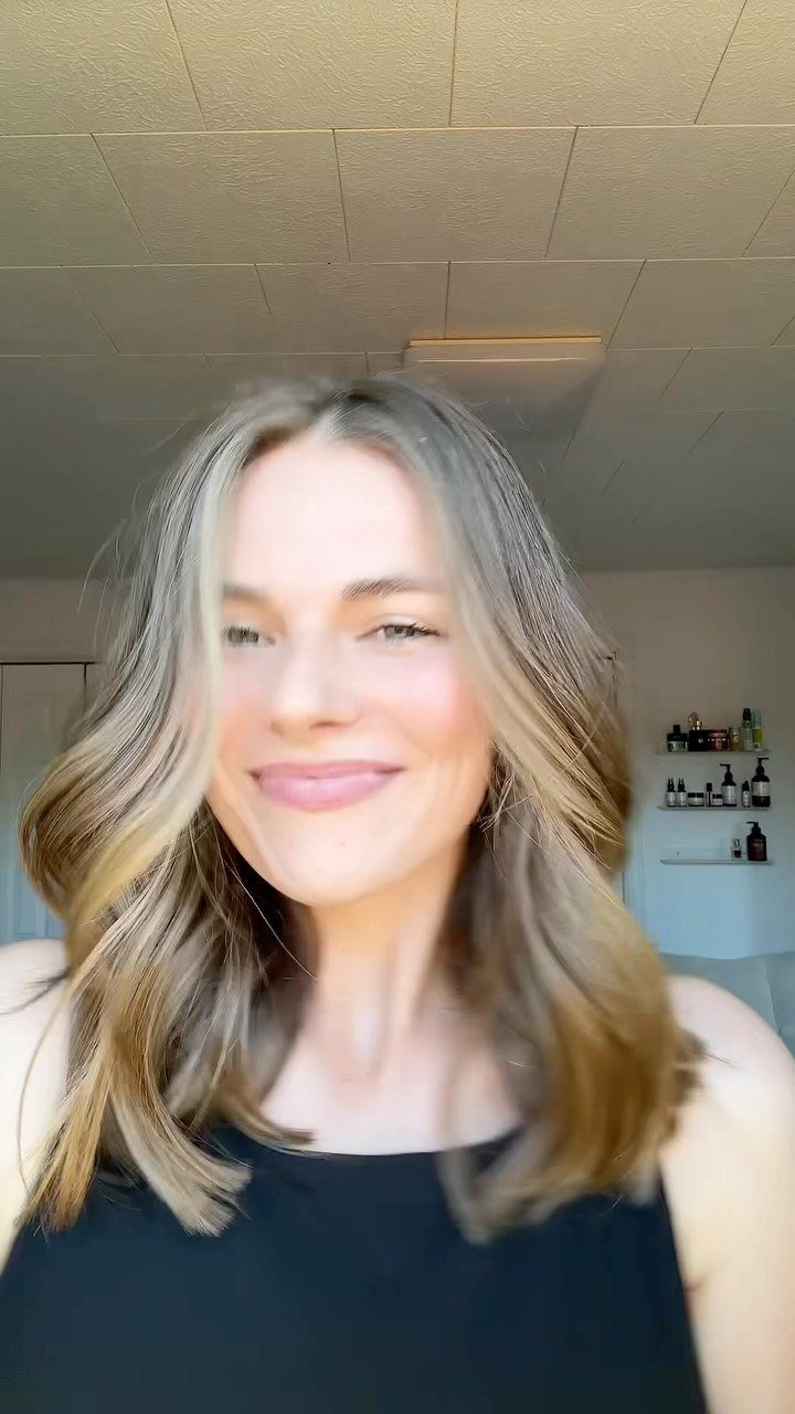 Woman posing with long, loose brown waves and lighter face-framing strands