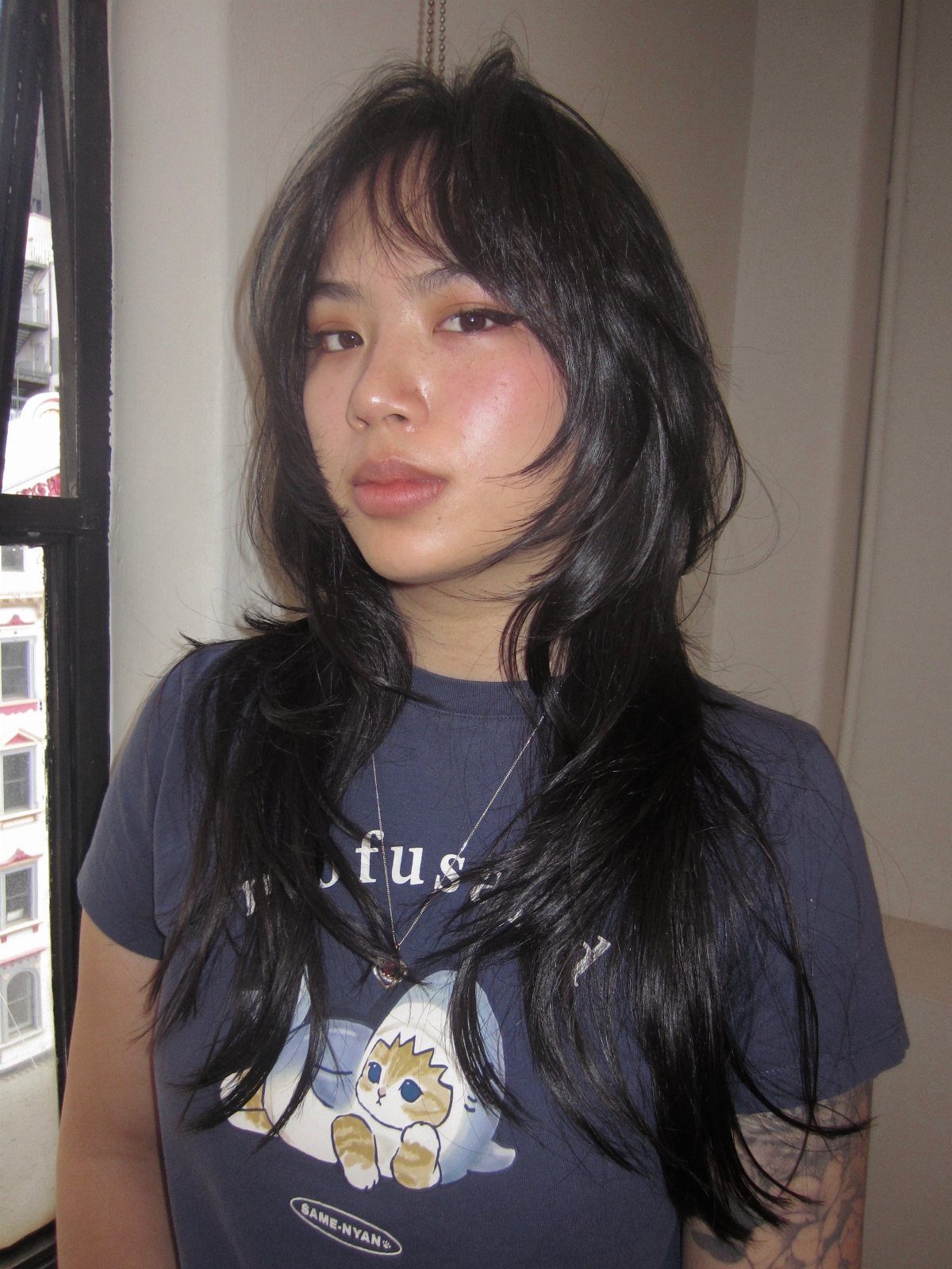 Woman showing long dark wavy wolf cut with shaggy layers and curtain bangs