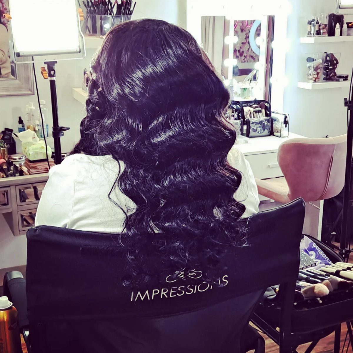 Long dark hair styled in glossy, defined waves in a salon