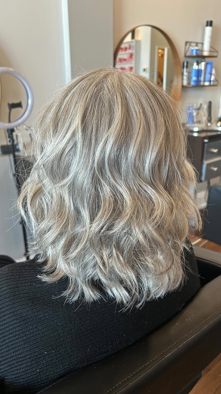 Tousled silver-blonde shoulder-length waves styled in a shaggy lob