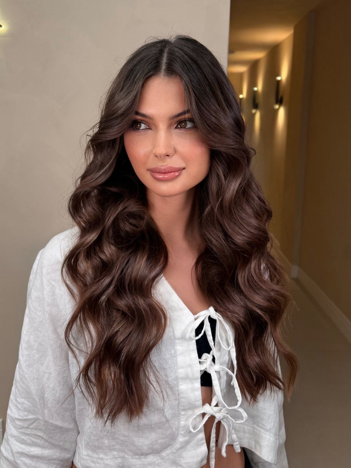 Woman with long dark wavy hair and soft face-framing layers