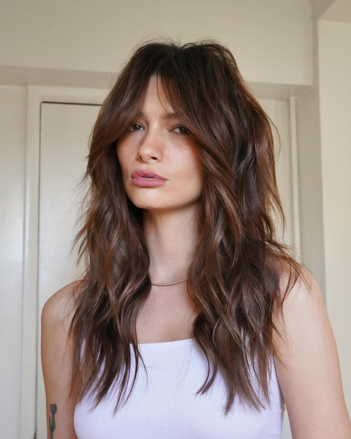 Woman showcasing wavy shag haircut with face-framing curtain bangs