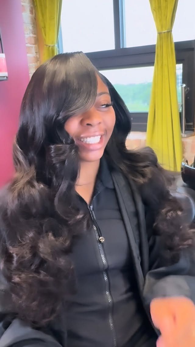 Woman displaying long dark tousled waves with side-swept bangs indoors