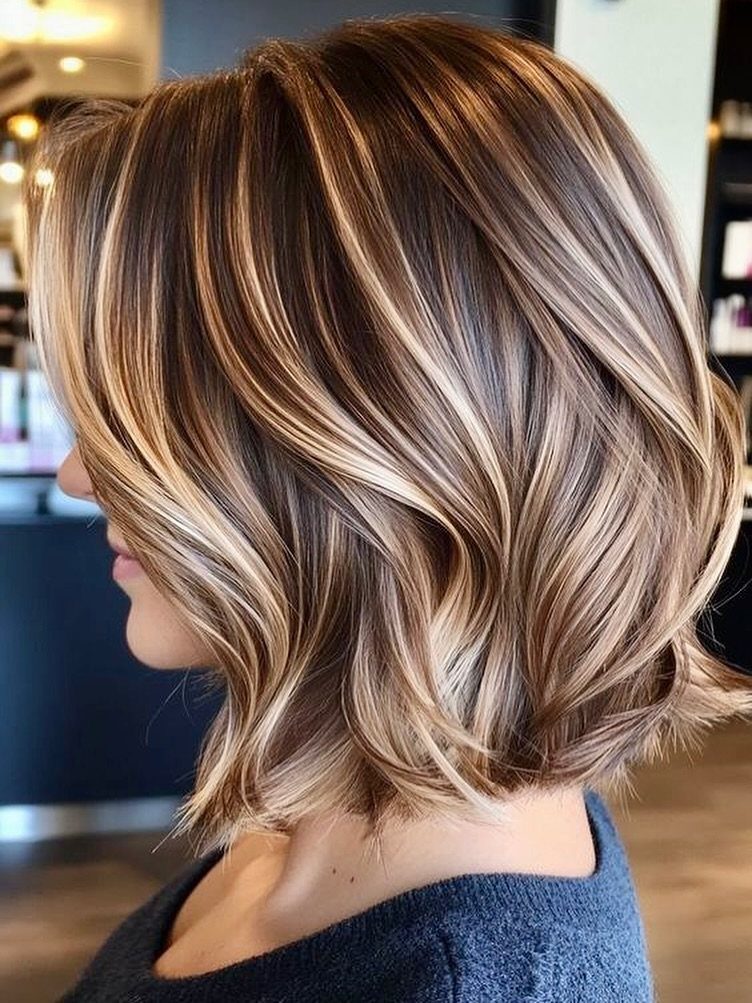 Layered blonde-highlighted wavy lob with textured ends shown from the side
