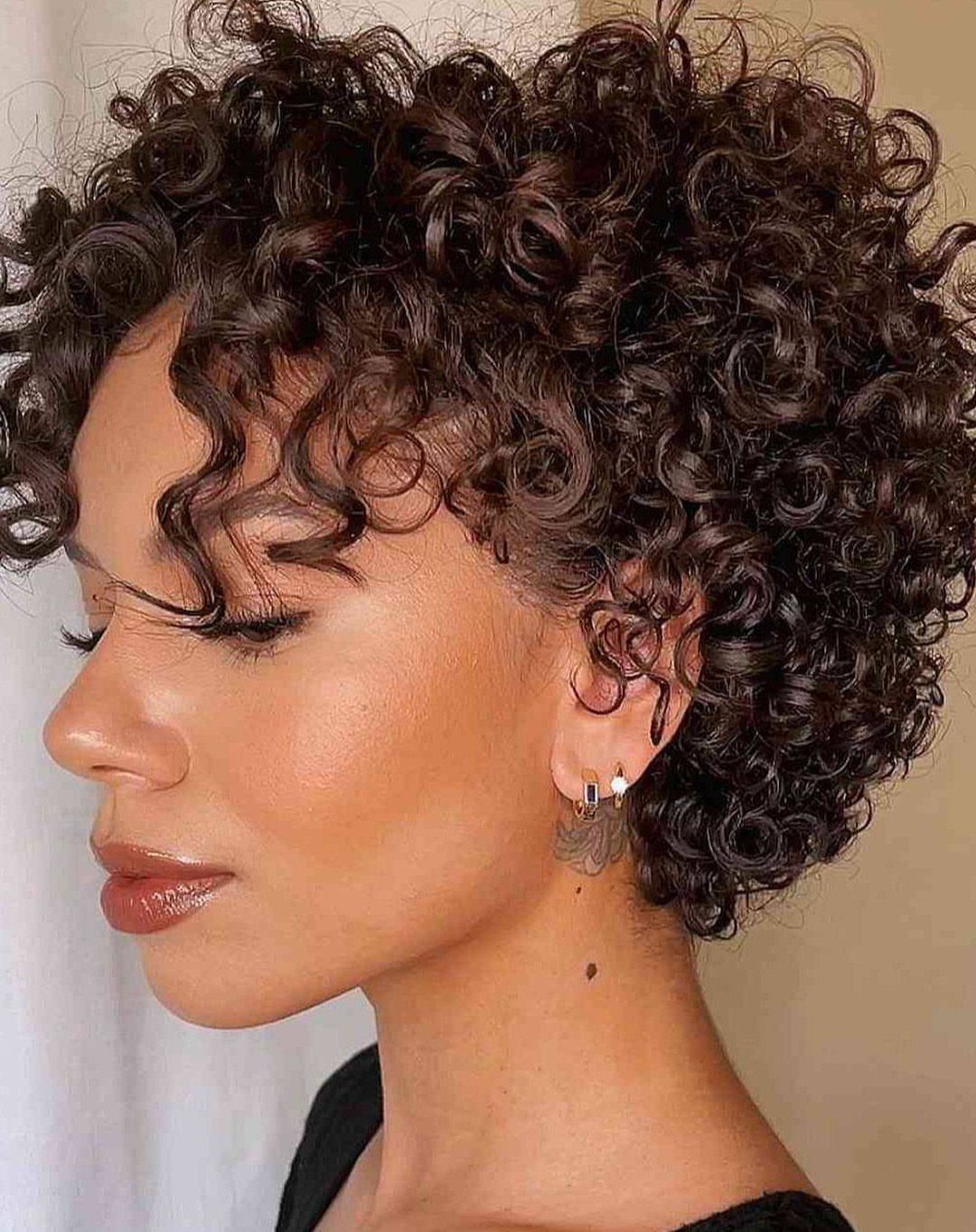Short curly pixie with side-swept curls framing the forehead