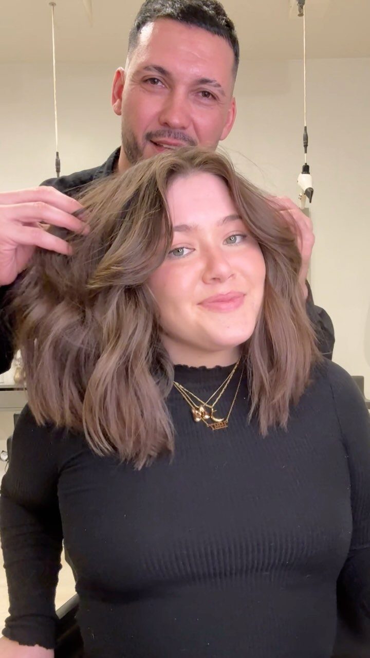 Woman displays a shoulder-length wavy brown lob as a man lifts her hair