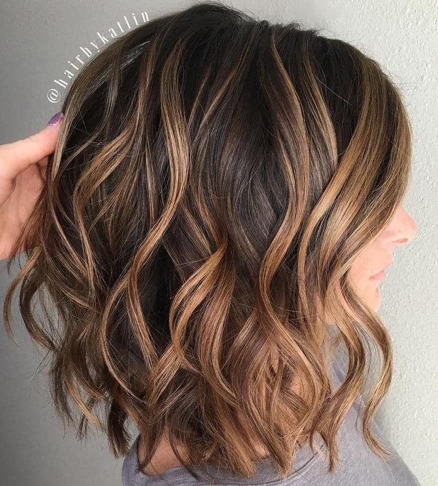 Shoulder-length brunette waves with caramel highlights and layered ends